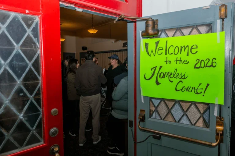 Sign reading “Welcome to the 2026 Homeless Count” on an open door with people inside.