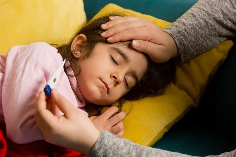 Sick child sleeping as an adult checks her temperature.