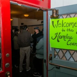 Sign reading “Welcome to the 2026 Homeless Count” on an open door with people inside.
