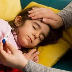 Sick child sleeping as an adult checks her temperature.